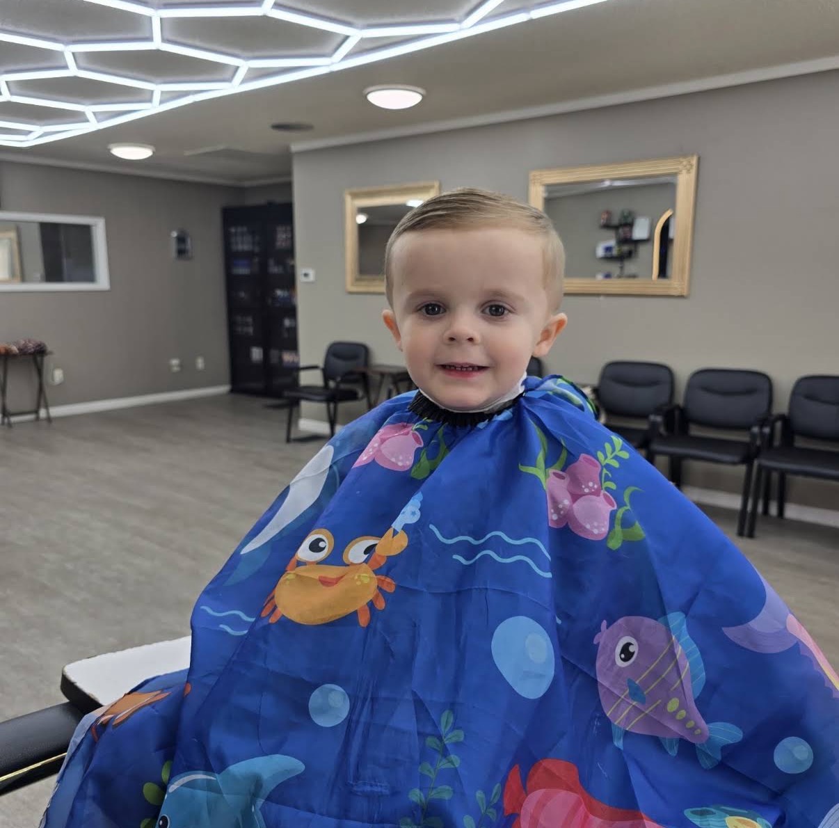 Young child smiling in the barber chair at Sam's Barbershop